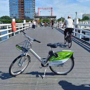 Bridge at Kiel's main station connecting Kiel's east and west side. Some people crossing the bridge and bicycle in front can be seen.