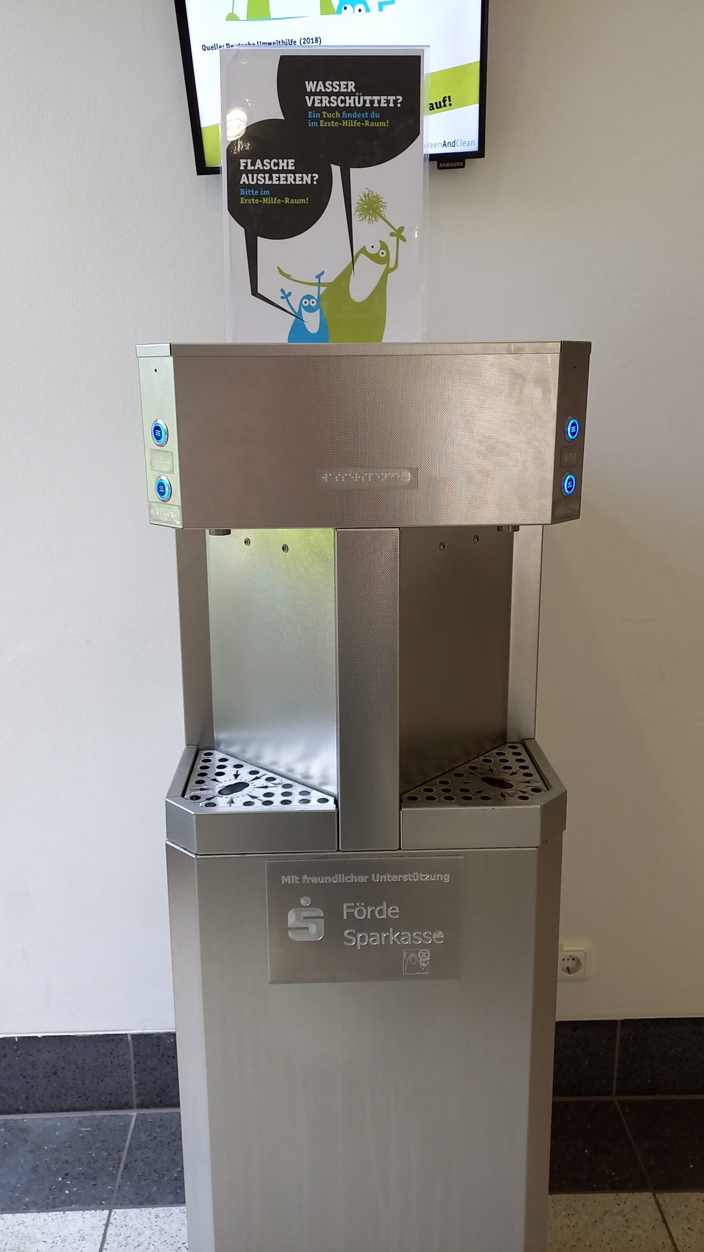 A water dispenser with two slots for water bottles. There's carbonated and non-carbonated water available.